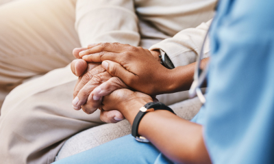 A nurse holds hands with an elderly patient