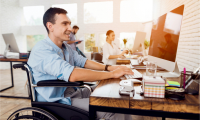 Disabled person in the wheelchair works in the office at the computer.