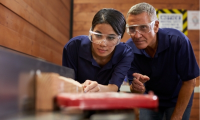 An apprentice being overseen by business owner while working in a workshop