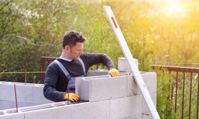Male builder stacking breeze blocks on top of each other on a sunny day