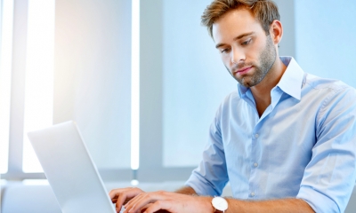 Young business executive using his laptop computer to work through some paperwork Young business executive using his laptop computer to work through some paperwork