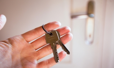 Buying another business Hand holding keys to door of newly purchased business