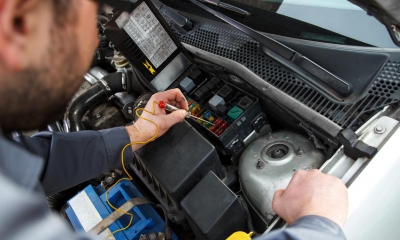 Mechanic improving car alarm capabilities under a bonnet of a car