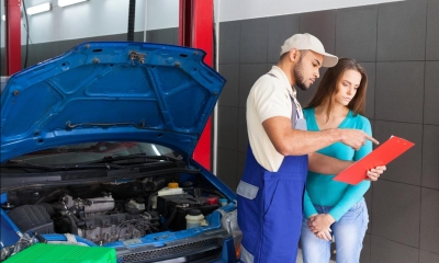 Car mechanic and customer stood next to car