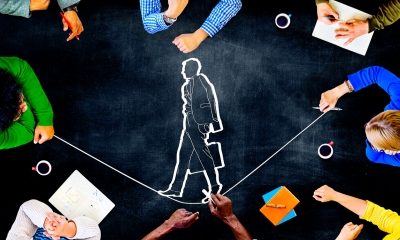 Carrying out health and safety risk assessments - checklist View from above of people sitting around a table surrounding an outline of a man walking a tightrope