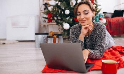 Young mum getting her Christmas shopping done on her laptop next to her Christmas tree
