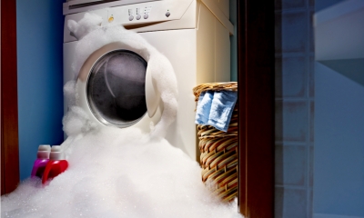 A broken washing machine with bubbles pouring out from it