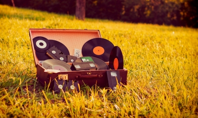 Suitcase lying in a field containing multiple vinyl records