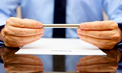 Person in a blue shirt holding a pen over a written statement of employment contract
