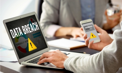 Man with smartphone and computer at table. Notification about threat of cyber attack on screens Man with smartphone and computer at table. Notification about threat of cyber attack on screens