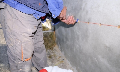 Male damp proofer in work gear filling in holes in a wall using a plastic bottle