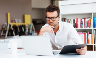 Design right and registration Man wearing glasses holding a tablet and looking at a laptop