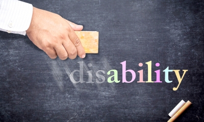 Man rubbing out 'disability' written in multicoloured chalk on a blakcboard