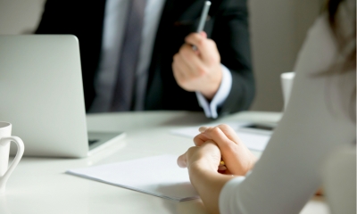 Man in a suit holding a pen disciplining a woman in a a white top