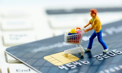 Toy man with shopping trolley on a black credit card on a keyboard