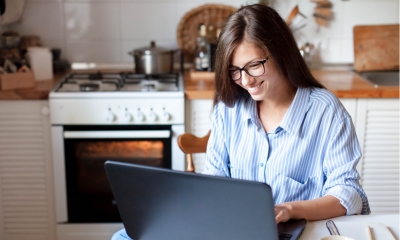 Young woman working from home office in a cozy kitchen
