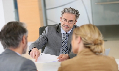 Two business owners meet with their lawyer to sign important contracts
