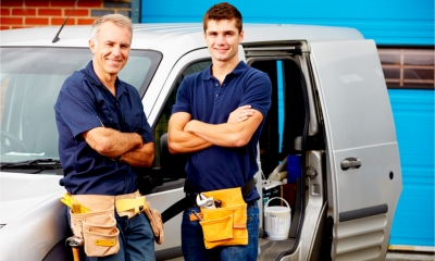 A father and son stand next the the family business van
