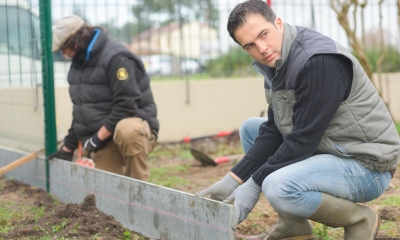 Two male fencing contractors measuring and building the foundations of a fence