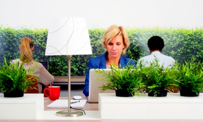 Woman in a blazer sat at a desk using her laptop