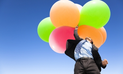 Floating your business Businessman floating into the air holding balloons
