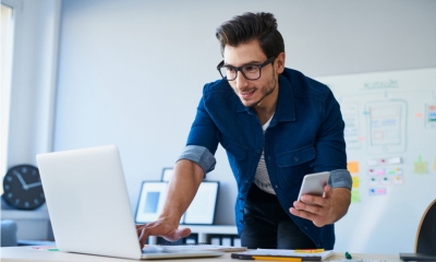 Freelancer at work using both his laptop and mobile