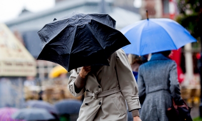 Woman walking to work in bad weather while holding a black umbrella