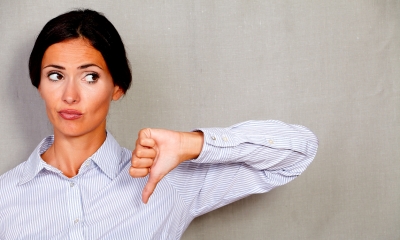 Woman in a blue and white striped shirt holding her thumb down