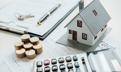 Little house with stacked-up coins next to a calculator