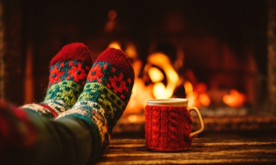 Person wearing woolly socks with their feet up by the fire while on holiday