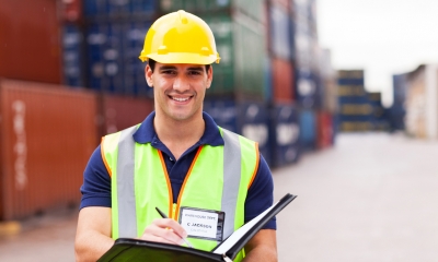 Importing and exporting Warehouse worker with clipboard in front of multiple shipping containers