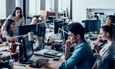 Working day in office. Group of young business people concentrating at their work while sitting at the large office desk in the office together Working day in office. Group of young business people concentrating at their work while sitting at the large office desk in the office together