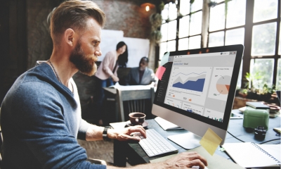 Businessman sat in front of a computer screen looking at financial analysis graphs