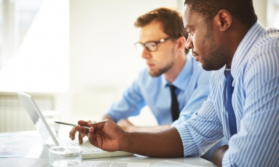 Two men in shirts and ties looking at a laptop