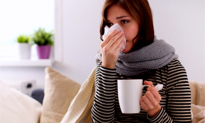 An employee blows her nose whilst drinking a hot drink