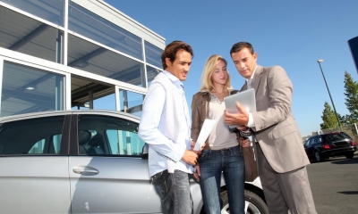 A motor dealer showing a legal contract to a couple at a motor dealership