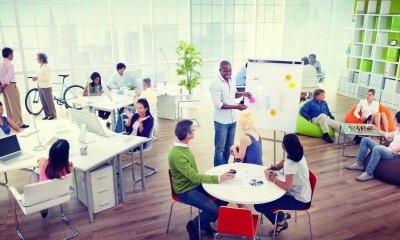 Multiple different people sat down in an open-plan styled office