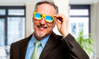 Man wearing glasses that show a beach at a holiday destination in the reflection