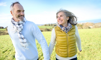 Pay and pensions Older couple hold hands while walking through a field