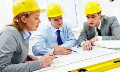Planning permission and building controls People in hard hats looking at building plans