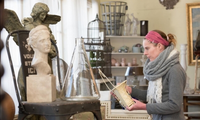 Woman holding vase in antique shop with antique items in background