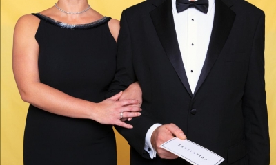 Man in black suit and woman in black dress with yellow background