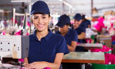 Woman in blue cap working in factory using sewing machine