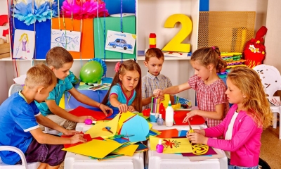 Multiple children at nursery drawing on coloured paper