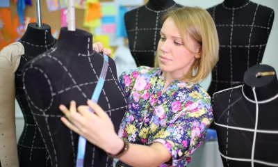 Woman in colourful shirt measuring manikin with blue tape