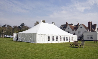 White marquee in grass field with houses in background