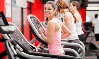 Multiple woman on treadmill jogging in gym with red walls