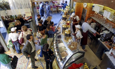 Multiple people stood in ice cream parlour being served by employees