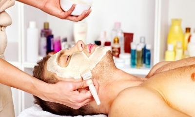 Man getting face mask painted on by a beautician