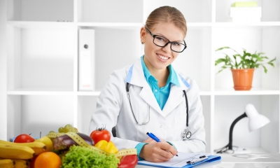 Nutritional therapist writing on clipboard with fruit and vegetables in front of her